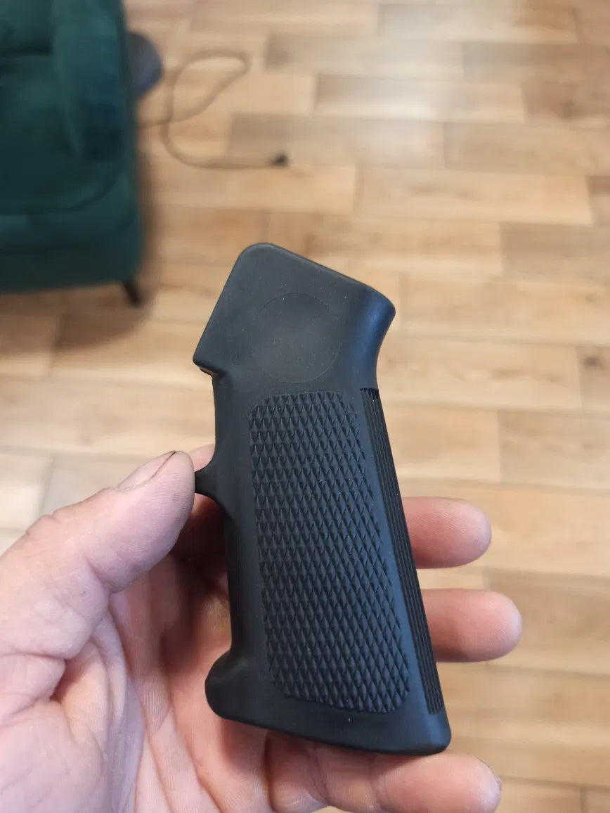Black textured grip held in a hand on a wooden floor background