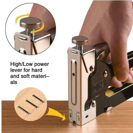 Stapler gun for hard and soft materials, used on a wooden surface.