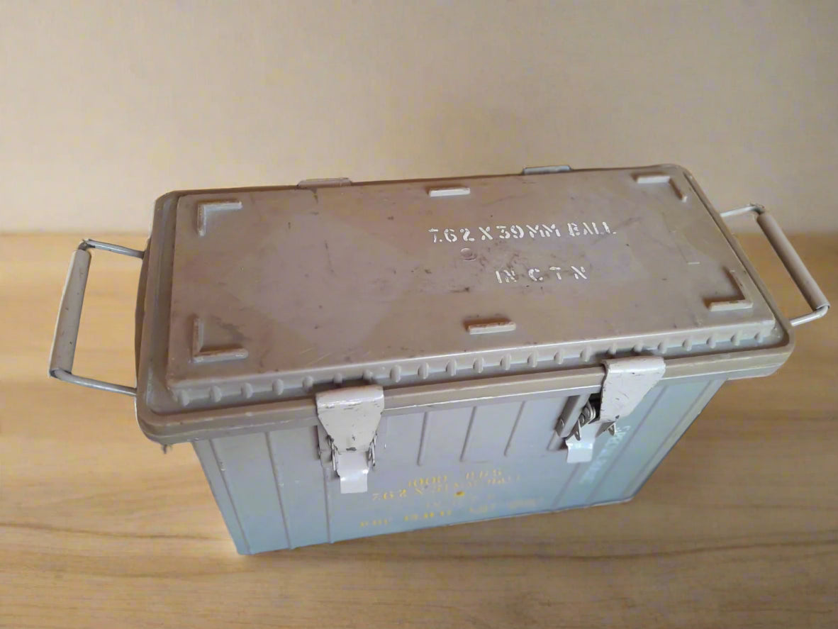 Metal ammunition box with text on a wooden surface