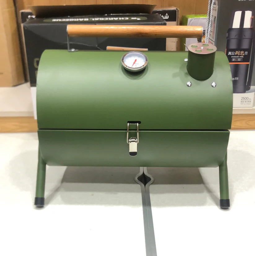 Green barrel-style barbecue grill with a thermometer