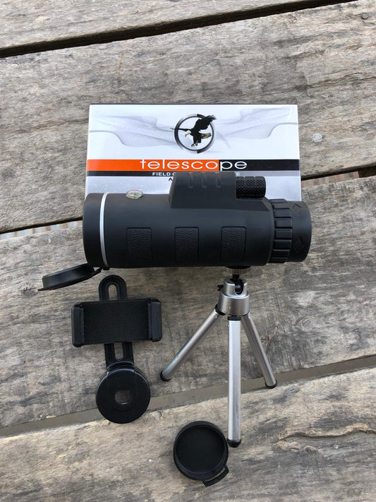 Black monocular telescope with tripod and phone mount on a wooden surface, branded 'telescope field'.