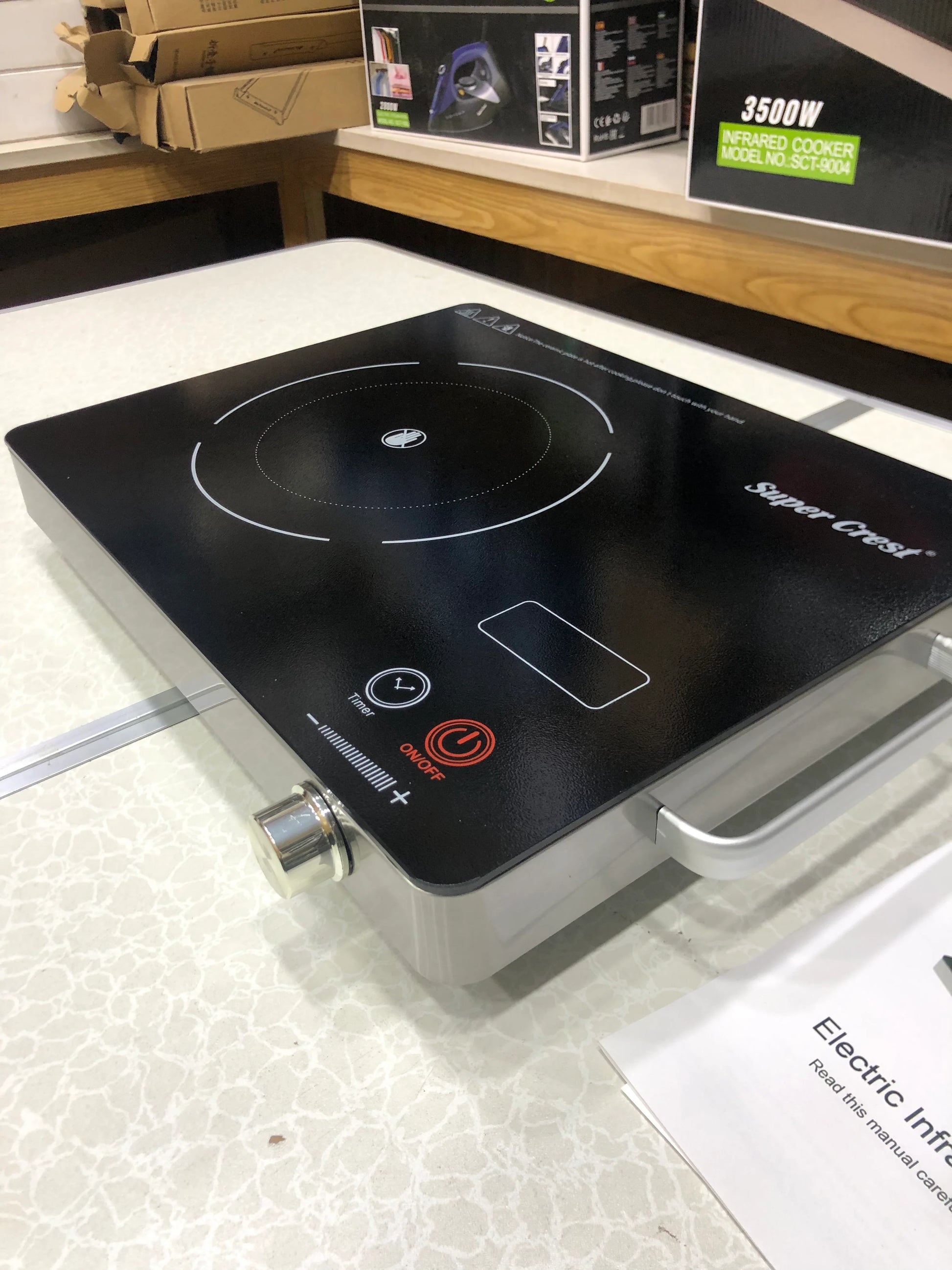 Portable electric induction cooktop on a display surface with packaging in the background