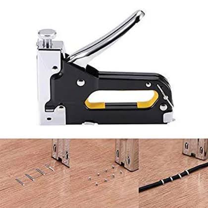Black and silver staple gun with accessories on a wooden surface