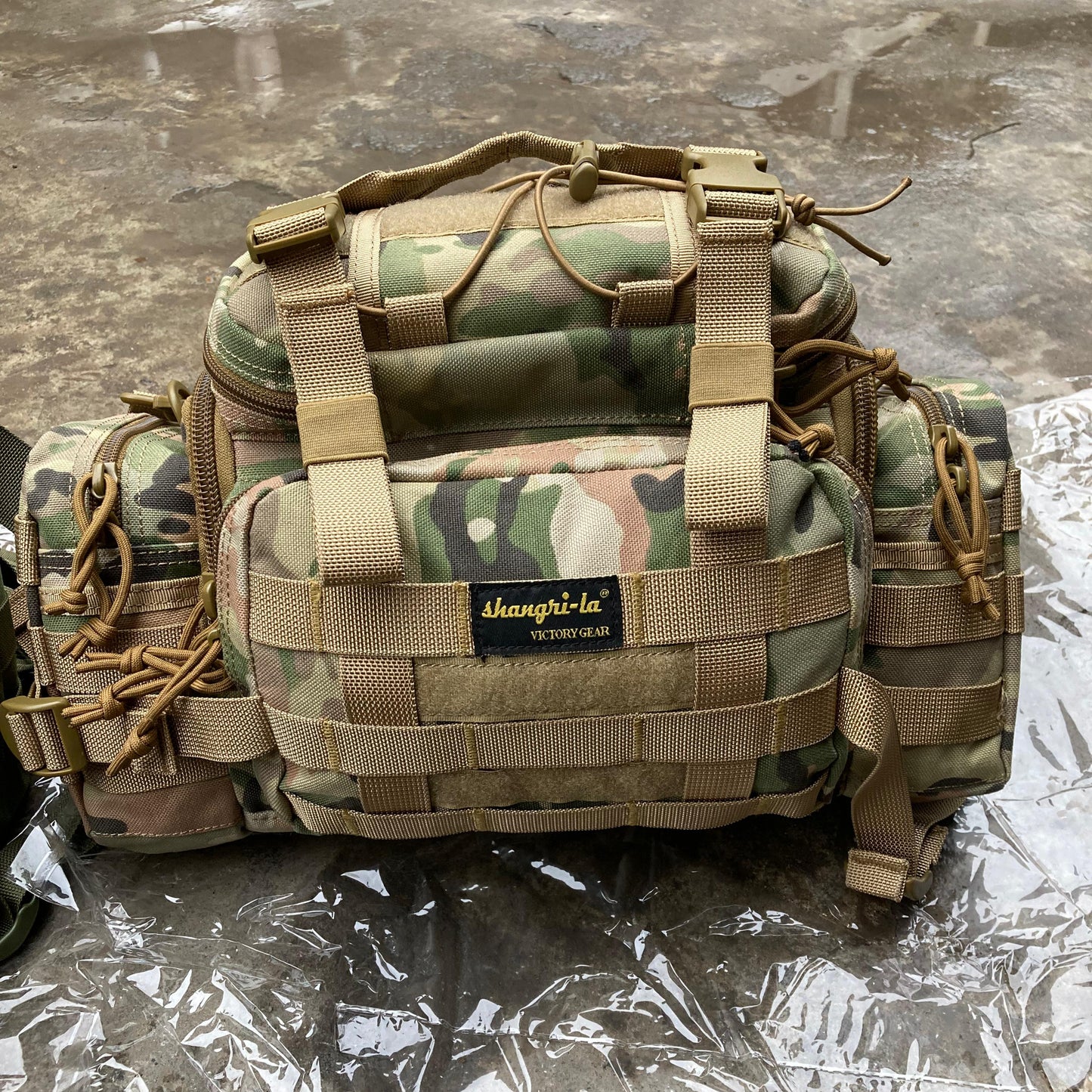 Camouflage tactical bag with visible brand logo on a reflective surface